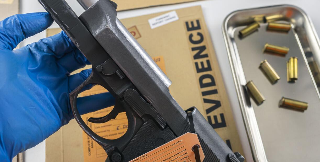 Scientific police officer examining gun in ballistic laboratory